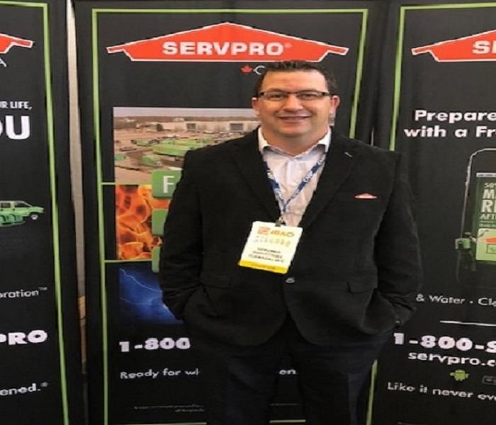 male in suit standing in front of display banner